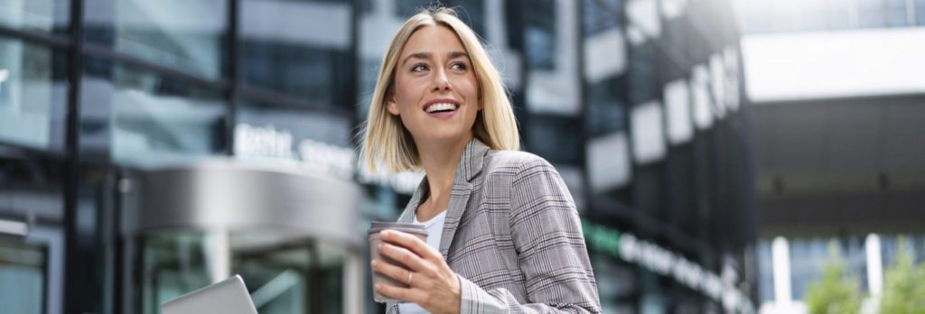 Smiling young businesswoman using laptop in the city